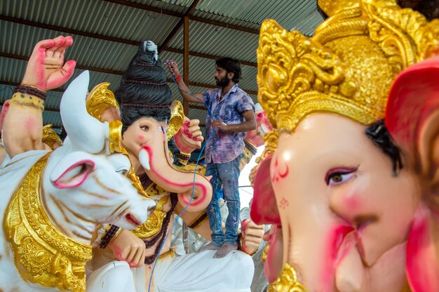 Artysta wykonujący rzeźbę i wykańczający figurkę hinduskiego boga Pana Ganesha w warsztacie artysty na festiwal Ganesha