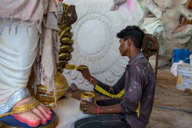 Artysta wykonujący rzeźbę i wykańczający figurkę hinduskiego boga Pana Ganesha w warsztacie artysty na festiwal Ganesha