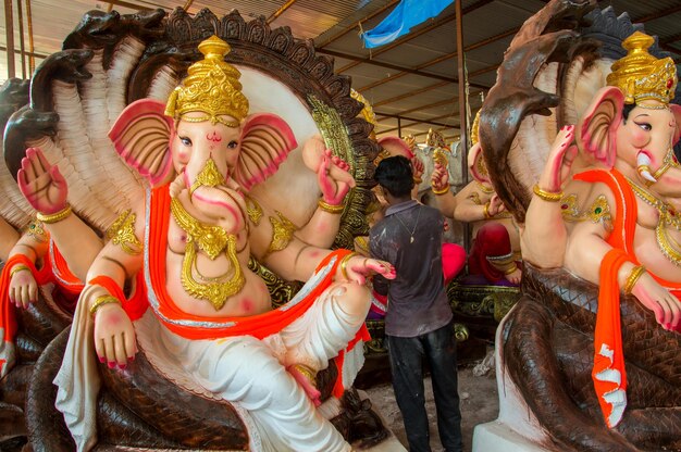 Artysta wykonujący rzeźbę i wykańczający figurkę hinduskiego boga Pana Ganesha w warsztacie artysty na festiwal Ganesha