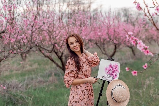Artystka maluje sad brzoskwiniowy w sadzie brzoskwiniowym wiosna