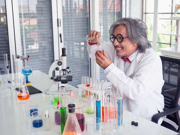 Asia naukowy badacz trzyma próbnej tubki jasny rozwiązanie w lab