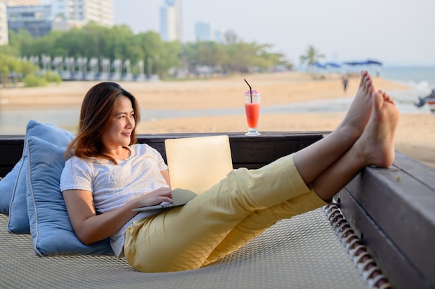 Asian businesswoman pracy online na plaży. Freelancer wykorzystujący technologię do pracy wszędzie. Nowy normalny styl życia po Covid-19.