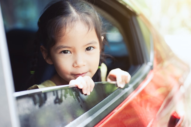 asian girl uśmiechając się i bawiąc się podróżować samochodem i patrząc z okna samochodu