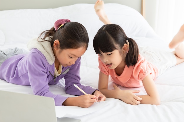 Asian Little Girl Czytanie Książki Na łóżku Z Komputera Notebook Razem