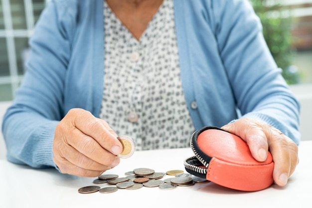 Asian senior lub starsza starsza kobieta trzyma liczenie monet w torebce. Ubóstwo, problem oszczędzania na emeryturze.