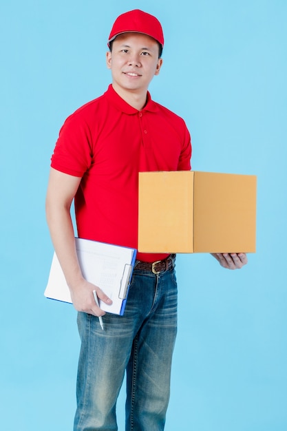 Asian szczęśliwy dostawa człowiek ubrany w czerwoną koszulę stojąc trzymając pudełka paczek papieru.