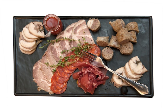 Asortyment kawałków mięsa z rozmarynem i sosem na prostokątnym marmurowym talerzu