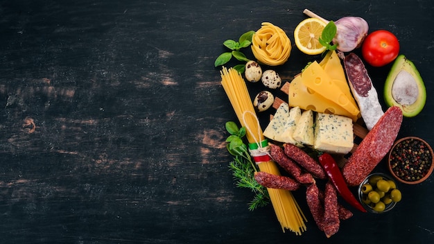 Asortyment kiełbasy, sera i świeżych warzyw Kuchnia włoska Na czarnym drewnianym tle Widok z góry Kopiowanie miejsca