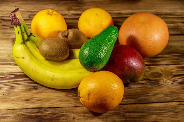 Asortyment owoców tropikalnych na drewnianym stole Martwa natura z bananami mango pomarańcze grejpfrut awokado i owoce kiwi