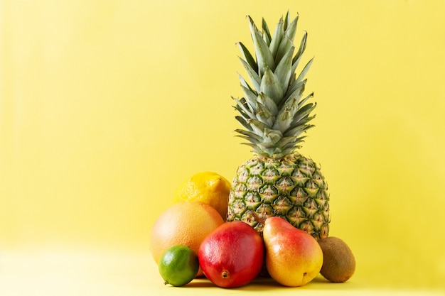 Asortyment Owoców Tropikalnych Na żółtym Tle: Ananas, Grejpfrut, Gruszka, Mango, Limonka, Cytryna I Kiwi