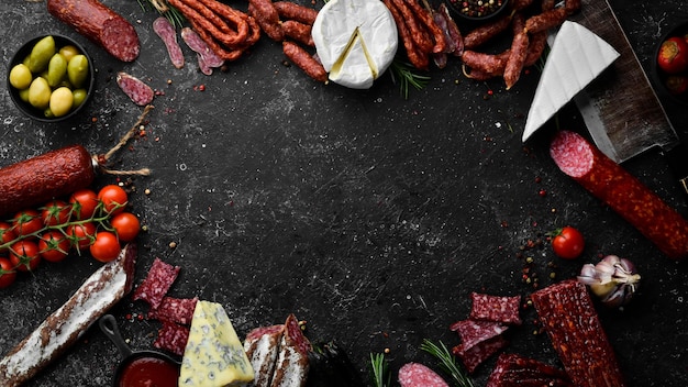 Asortyment przypraw salami serowych i produktów mięsnych na czarnym tle Widok z góry Wolne miejsce na tekst