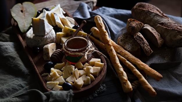 Asortyment serów na drewnianej desce podawany z miodem owocowym i pieczywem