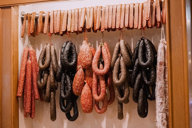 Zdjęcie asortyment wędzonej kiełbasy i salami wiszące w supermarkecie delikatesy i sklep mięsny