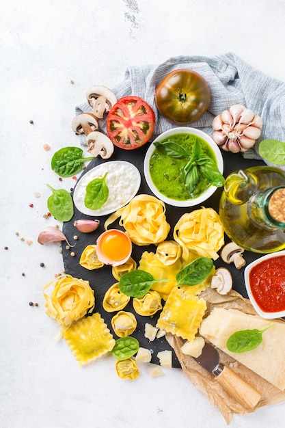 Asortyment włoskich potraw i składników ravioli z ricottą i szpinakiem makaron tortellini pesto sos pomidorowy oliwa z oliwek parmezan