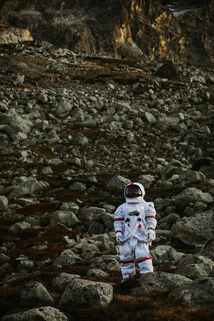 Astronauta stojący na lądzie przeciwko górze