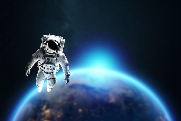 Astronauta w białym skafandrze kosmicznym wiszącym w kosmosie na tle planety Ziemia Kopiuj przestrzeń