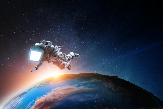 Astronauta z głową vintage TV na spacewalk na orbicie planety. Różne środki przekazu.