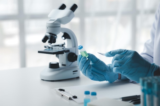Zdjęcie asystent laboratoryjny, naukowiec medyczny, chemik, trzyma szklaną rurkę przez chemiczną probówkę, przeprowadza eksperyment chemiczny i bada próbkę pacjenta koncepcja medycyny i badań