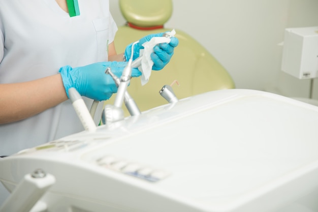 Asystent w rękawiczkach czyści narzędzia dentystyczne