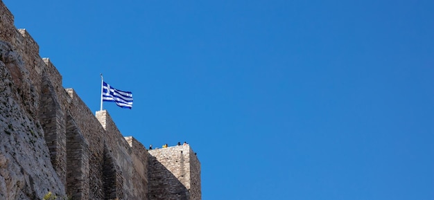 Ateny Grecja Akropol skała Grecka flaga macha na banerze jasnego nieba