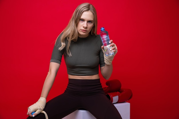 Athletic młoda kobieta pije wodę po treningu bokserskim