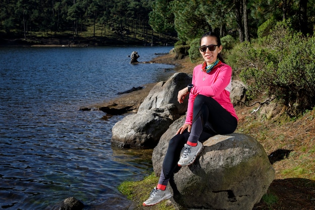 Atleta Descansando A La Orilla De Un Lago Sentada Sobre Una Piedra Despus De Correr En El Bosque