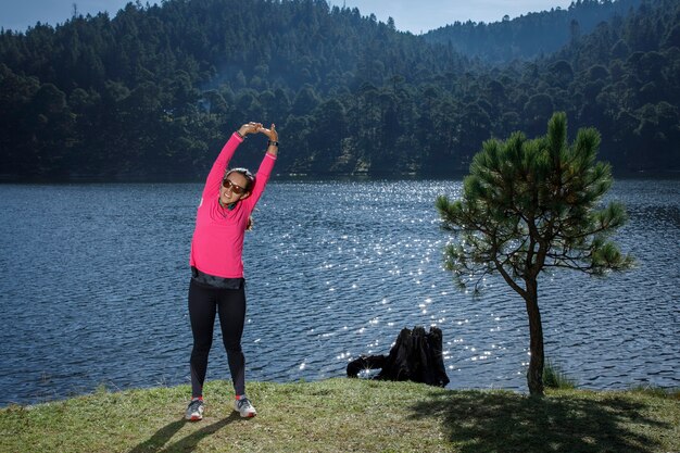 Atleta estirando despues de correr a la orilla de un lago