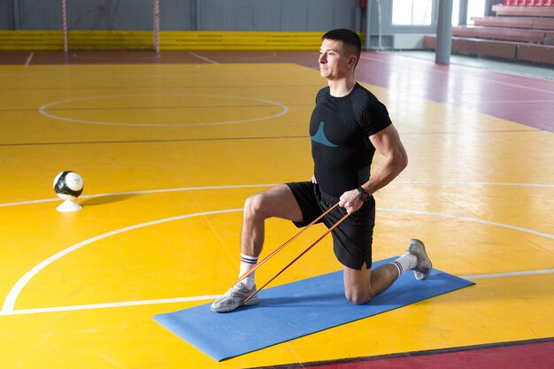 Atletyczny facet w sportowej i fitness tracker robi ćwiczenia w siłowni.