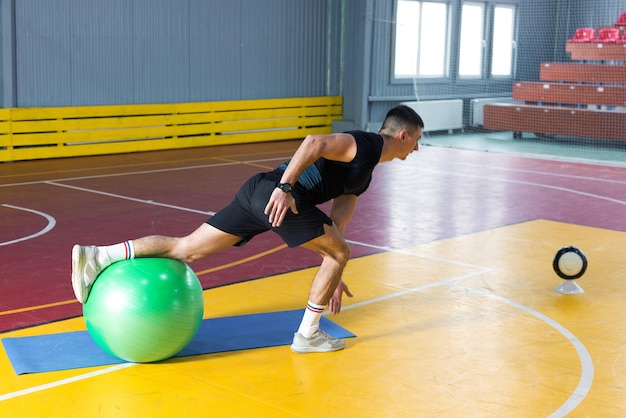 Atletyczny facet w sportowej i fitness tracker robi ćwiczenia w siłowni.