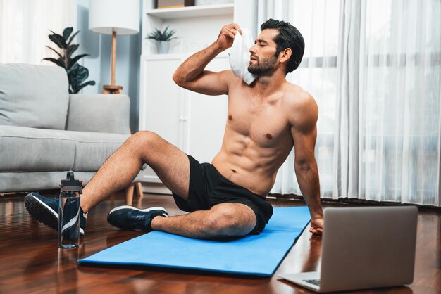 Atletyczny i sportowy mężczyzna siedzący na matce fitness w domu wesołości