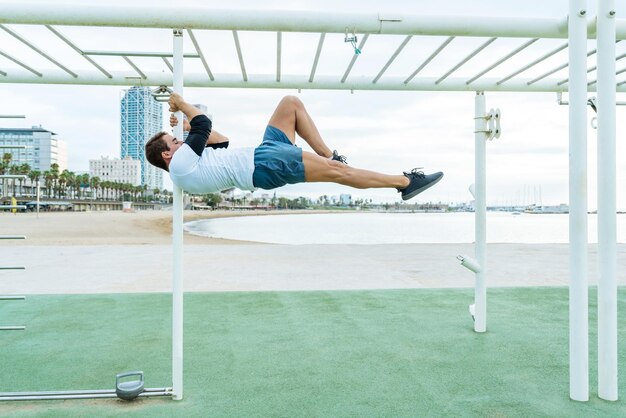 Zdjęcie atletyczny mężczyzna robi ćwiczenia funkcjonalne na siłowni na świeżym powietrzu