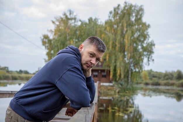 Atletyczny mężczyzna stojący na moście miejskim nad rzeką i patrzący w kamerę