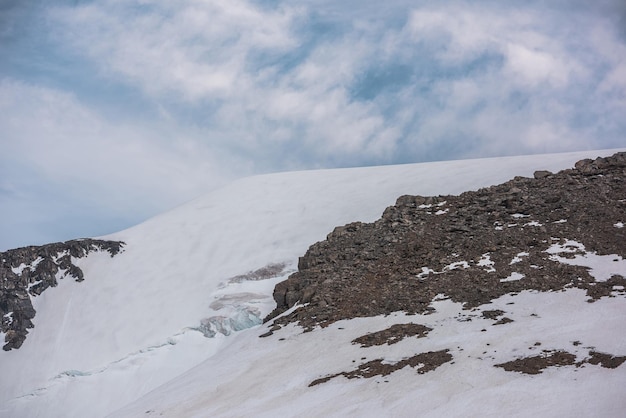 Atmosferyczny Krajobraz Z Wysoką śnieżną Górą Z Ostrymi Skałami Pod Chmurami Cirrus Na Niebieskim Niebie Piękna Alpejska Sceneria Z Dużą śnieżną Górą Pod Spindrift Pochmurne Niebo Przy Zmiennej Pogodzie