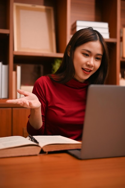 Atrakcyjna azjatycka bizneswoman korzystająca z laptopa podczas konferencji online ze swoim zespołem