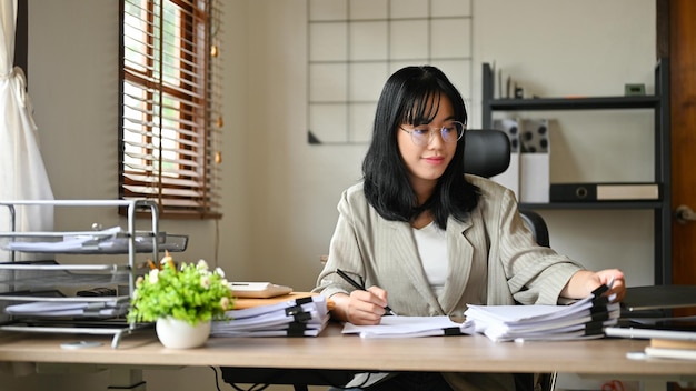Atrakcyjna azjatycka bizneswoman pracująca przy biurku, zarządzająca swoim raportem księgowym