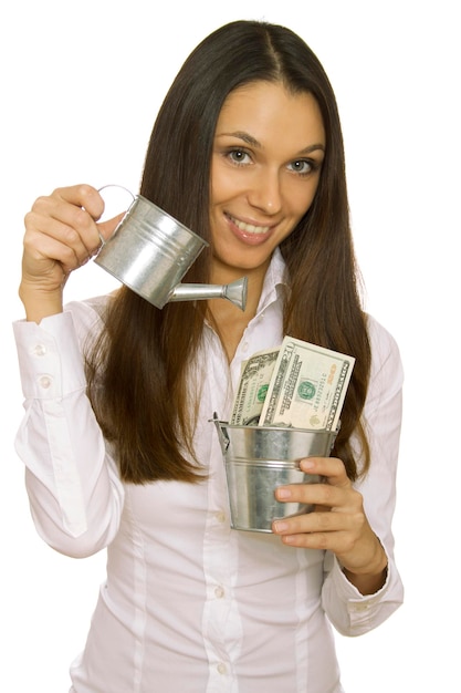 Atrakcyjna biznesowa kobieta trzyma pieniądze w wiadrze i nalewa ikhi z konewki izolowany na białym tle