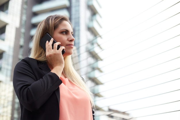 Atrakcyjna bizneswoman rozmawia z telefonem komórkowym w środowisku miejskim