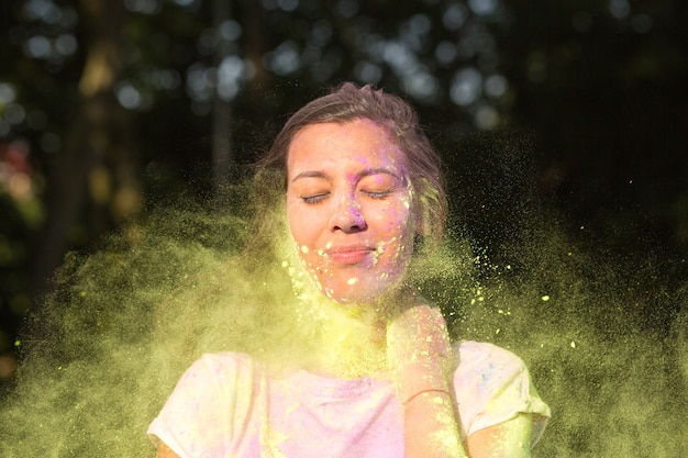 Atrakcyjna brunetka azjatycka kobieta w białej koszulce bawi się żółtym proszkiem Holi