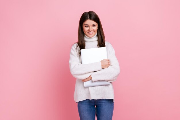 Atrakcyjna brunetka kobieta stojąca trzymając notatnik patrząc na kamerę z szczęśliwym wyrazem twarzy