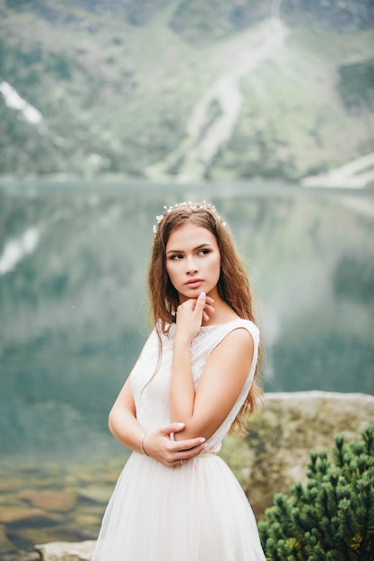 Atrakcyjna brunetka panna młoda w przepięknej białej sukni ślubnej stojącej nad jeziorem Morskie Oko