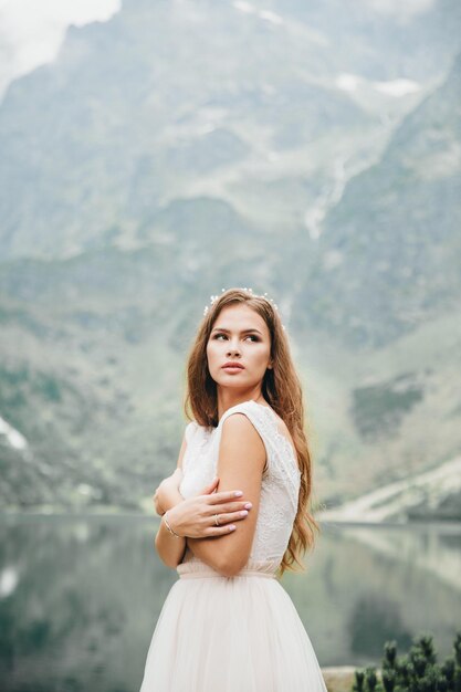 Atrakcyjna brunetka panna młoda w przepięknej białej sukni ślubnej stojącej nad jeziorem Morskie Oko