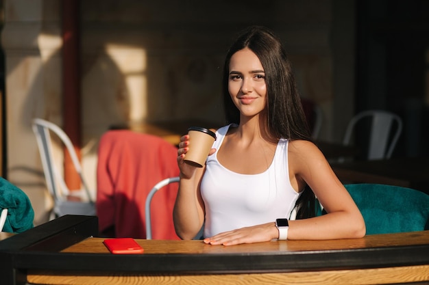 Atrakcyjna dziewczyna pije kawę na tarasie Piękna brunetka odpoczywa podczas przerwy