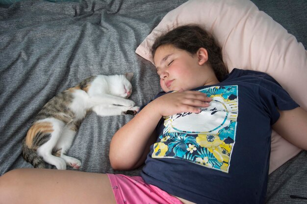 Atrakcyjna dziewczyna śpi na łóżku z kotem