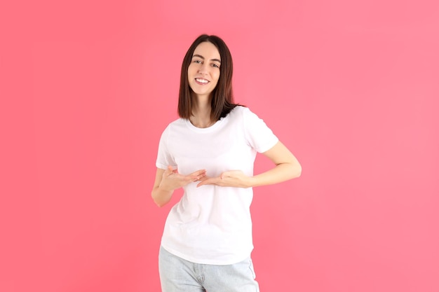 Atrakcyjna dziewczyna w białej koszulce na różowym tle