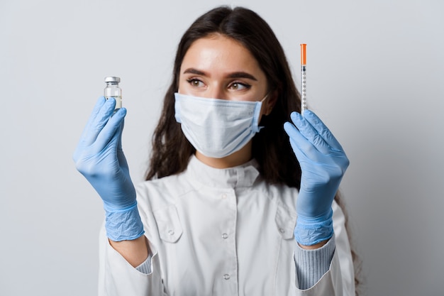 Atrakcyjna dziewczyna w rękawiczkach medycznych z strzykawką i lekiem. Lekarz posiadający szczepionkę na koronawirusa. Szczepienie Covid-19. Zatrzymaj kwarantannę.