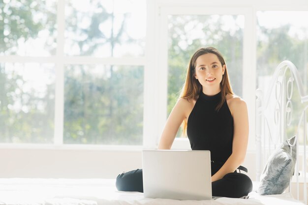 atrakcyjna kobieta korzystająca z laptopa i uśmiechająca się o poranku