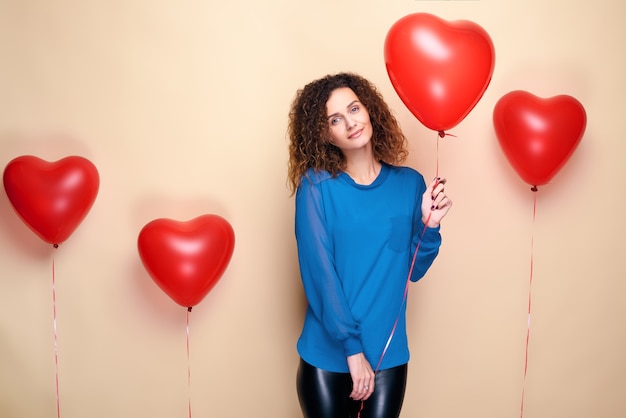 Atrakcyjna kobieta kręcone włosy trzymając balon w kształcie czerwonego serca