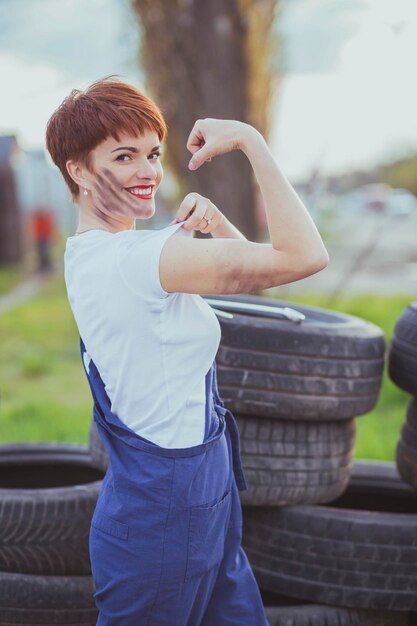 atrakcyjna kobieta mechanik w kombinezonie pokazuje bicepsy