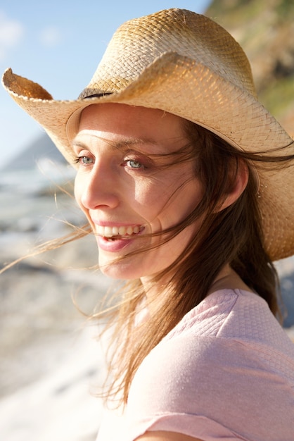 Atrakcyjna kobieta ono uśmiecha się z kapeluszem przy plażą