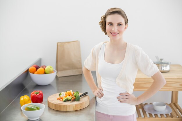 Atrakcyjna kobieta pozuje w jej kuchni z rękami na biodrach